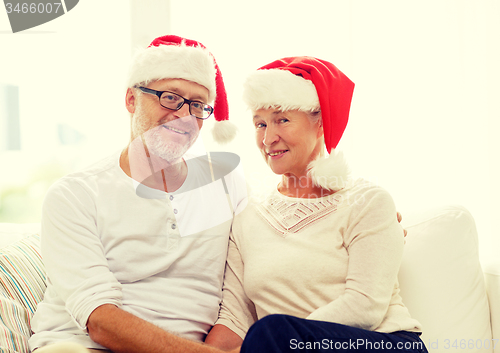 Image of happy senior couple in santa helper hats at home