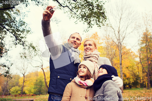 Image of happy family with camera in autumn  park