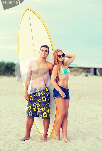 Image of smiling couple in sunglasses with surfs on beach