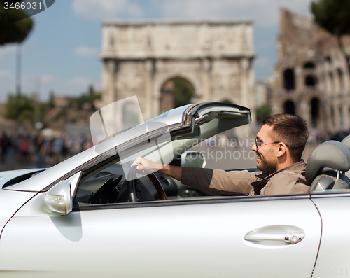 Image of happy man driving cabriolet car over city of rome