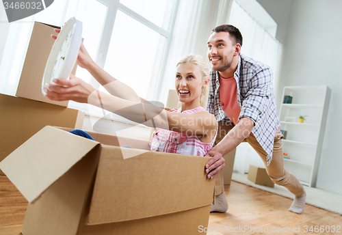 Image of couple with cardboard boxes having fun at new home
