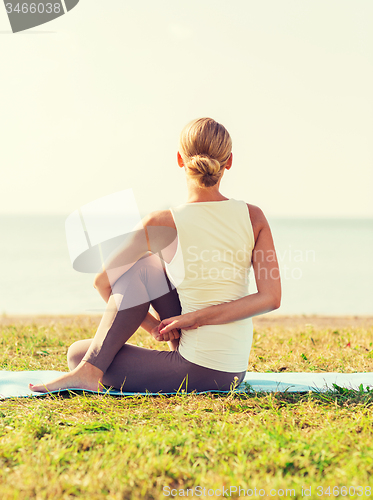 Image of woman making yoga exercises outdoors