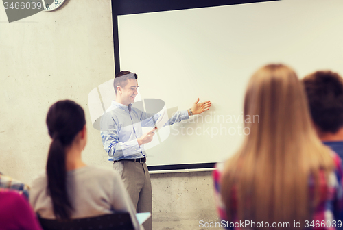 Image of group of students and smiling teacher with notepad