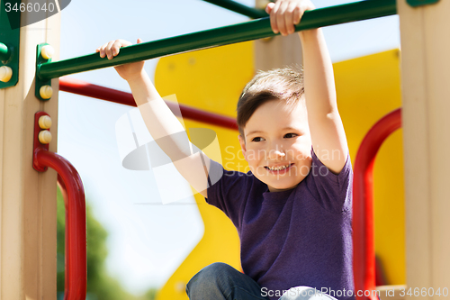 Image of happy little boy climbing on children playground