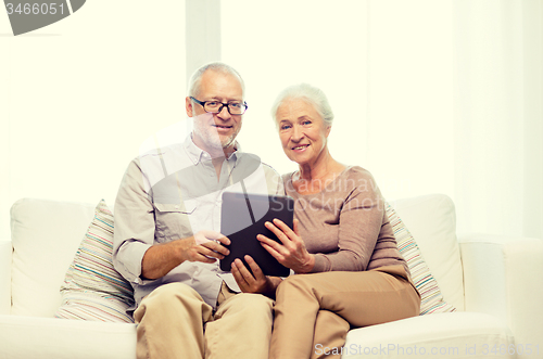 Image of happy senior couple with tablet pc at home