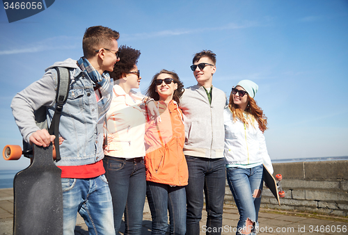 Image of happy teenage friends with longboards on street