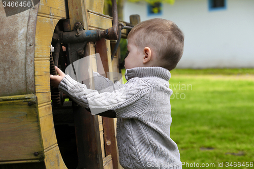 Image of 2 years old curious Baby boy managing with old agricultural Mach