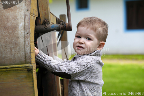 Image of 2 years old curious Baby boy managing with old agricultural Mach