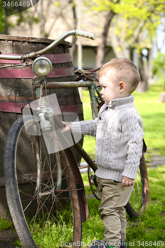 Image of 2 years old curious Baby boy walking around the old bike 