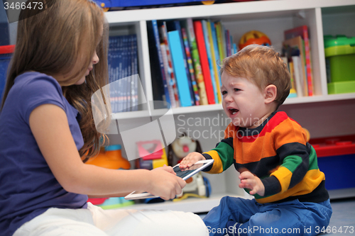 Image of girl and her little brother crying and arguing with a digital ta