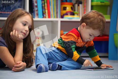 Image of Disappointing girl with her little brother using a digital table