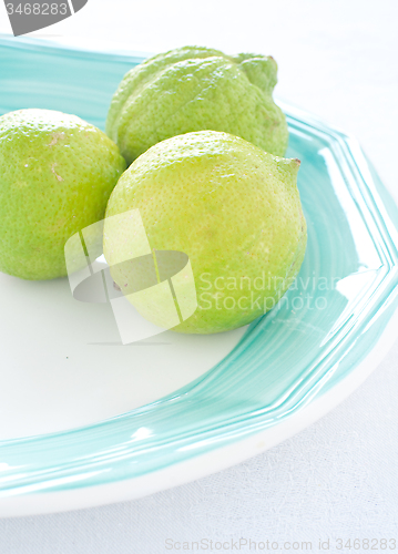 Image of group of green lemons on colored background
