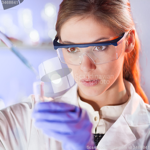 Image of Young scientist pipetting in life science laboratory.