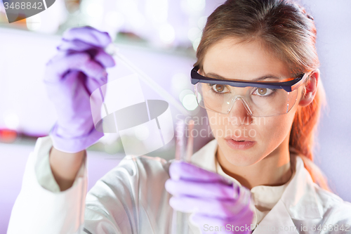 Image of Young scientist pipetting in life science laboratory.