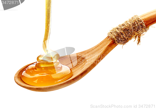 Image of honey pouring into wooden spoon