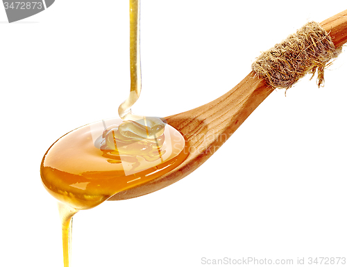 Image of honey pouring into wooden spoon