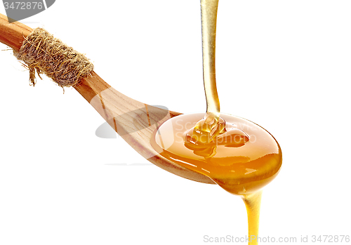 Image of honey pouring into wooden spoon