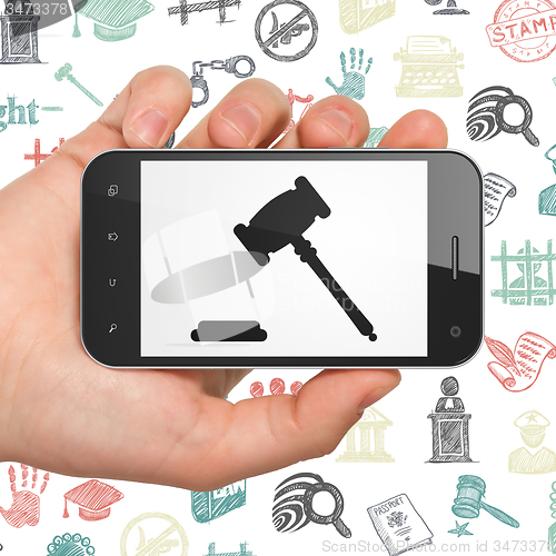 Image of Law concept: Hand Holding Smartphone with Gavel on display