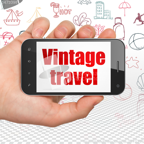 Image of Tourism concept: Hand Holding Smartphone with Vintage Travel on display
