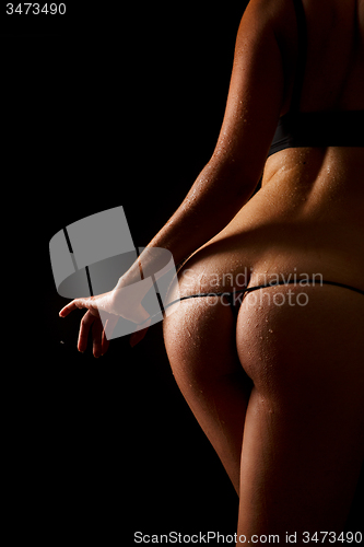 Image of Woman pulling off her underwear over black background.