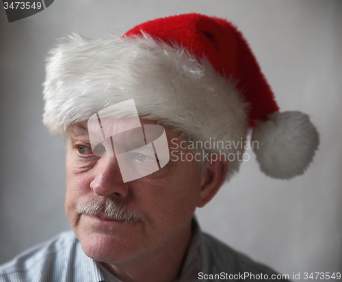 Image of annoyed senior with a Santa hat