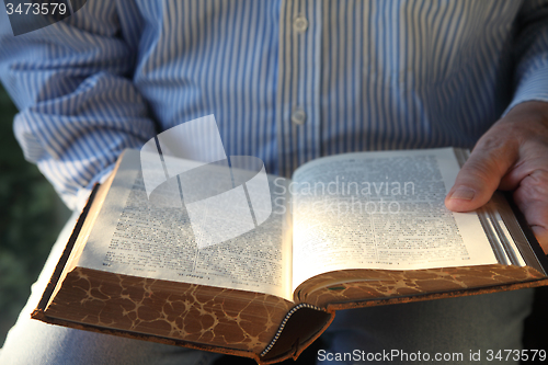 Image of man reading old German Bible in sunlight