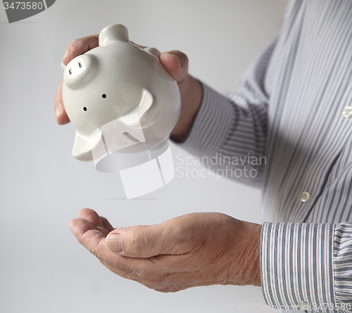 Image of businessman emptying piggy bank