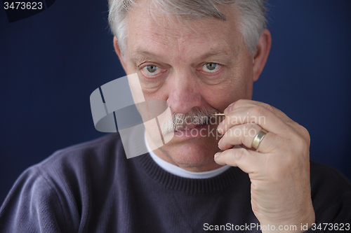 Image of senior man using toothpick  