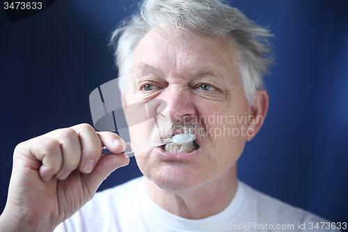 Image of Mature man brushes teeth. 