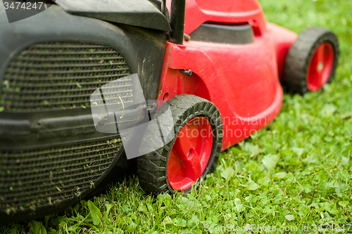 Image of red lawnmower on green grass