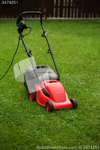 Image of red lawnmower on green grass