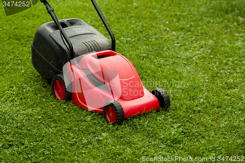 Image of red lawnmower on green grass