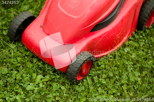 Image of red lawnmower on green grass