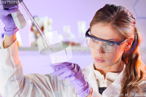 Image of Young scientist pipetting in life science laboratory.