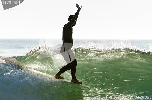 Image of Long boarder surfing the waves at sunset