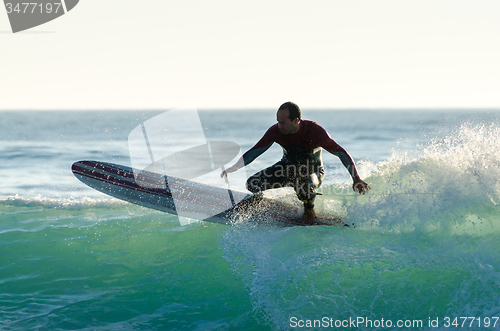 Image of Long boarder surfing the waves at sunset