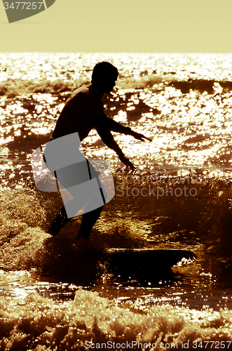 Image of Longboarder surfing at sunset