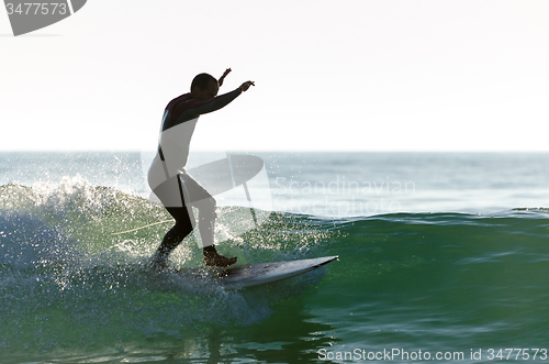 Image of Long boarder surfing the waves at sunset