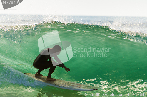 Image of Long boarder surfing the waves at sunset