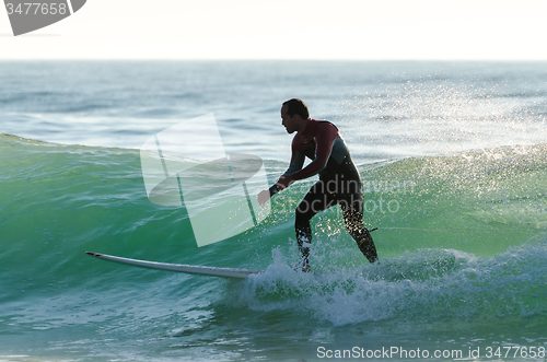 Image of Long boarder surfing the waves at sunset