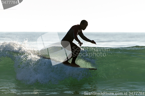 Image of Long boarder surfing the waves at sunset