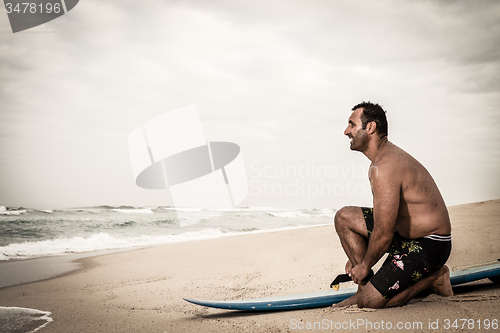 Image of Surfer tying his surfboard\'s leach