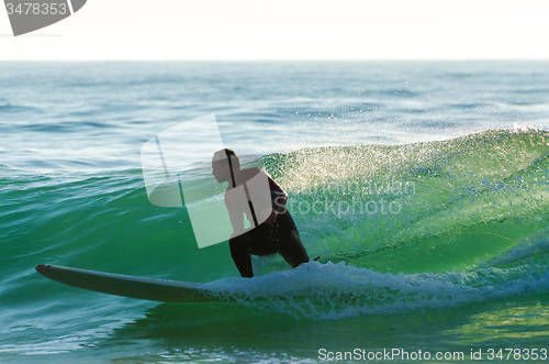 Image of Long boarder surfing the waves at sunset