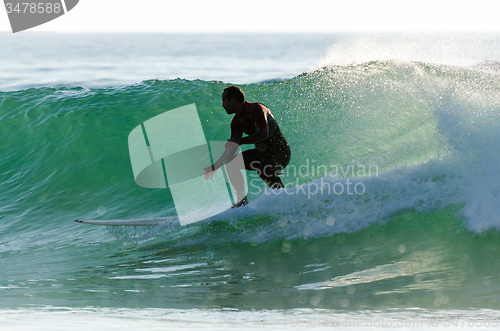 Image of Long boarder surfing the waves at sunset