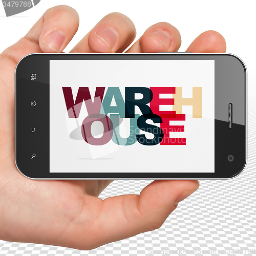 Image of Industry concept: Hand Holding Smartphone with Warehouse on  display