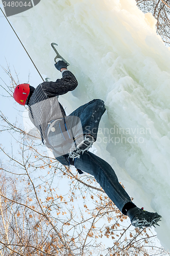 Image of Man climbs upward on ice climbing competition