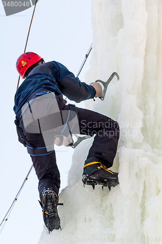 Image of Man climbs upward on ice climbing competition