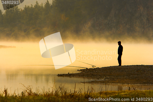 Image of Man Fishing at river shore