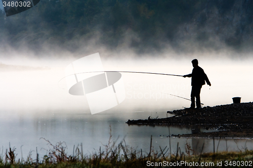 Image of Man fishing at river shore 