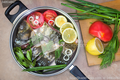 Image of Fish and components for her preparation in a large skillet.